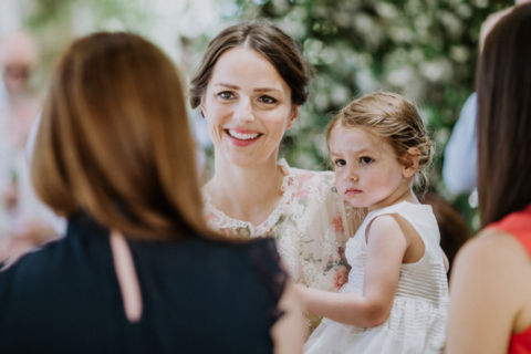 Hochzeitsfoto von Braut und Kind im Gespräch mit einem Gast