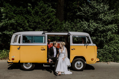Fotoaufnahme eines VW Bully mit Hochzeitspaar