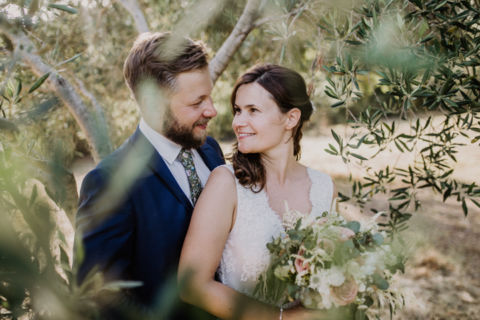 Foto durch Olivenzweige: Das Brautpaar im Portrait