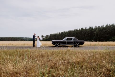 Hochzeitspaar tanzt vor Mustang