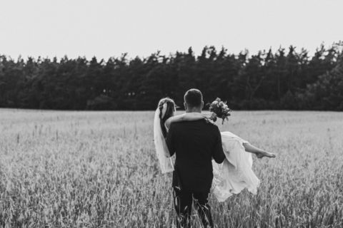 Bräutigam trägt die Braut durch das Kornfeld - Hochzeitsfoto