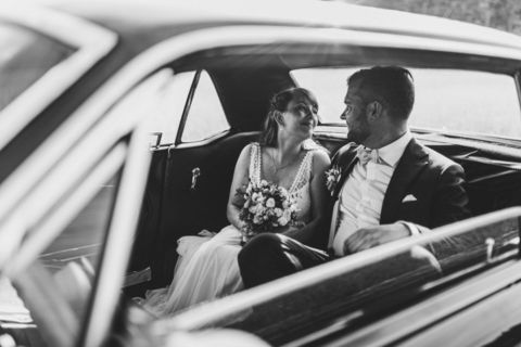 Brautpaar sitzt im Mustang auf der Rückbank
