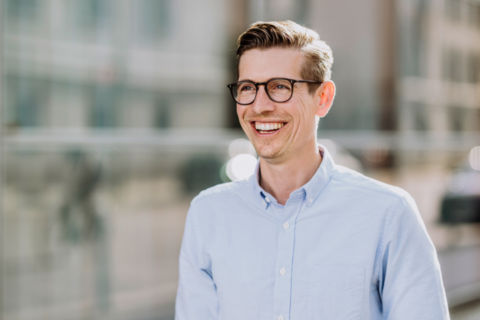 Businessfoto eines jungen Mannes vor einer Glasfassade